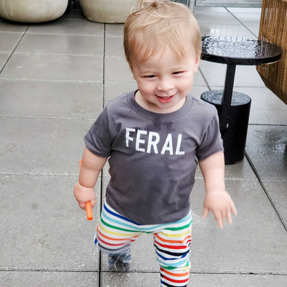 Funny Toddler T-Shirt: Happy child wearing FERAL t-shirt while playing outdoors, showcasing fun design and comfort.